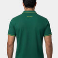 Man wearing a green polo shirt with a visible brand logo on the back against a white background