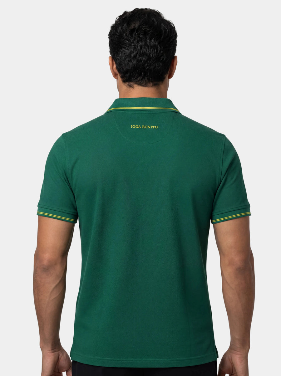 Man wearing a green polo shirt with a visible brand logo on the back against a white background