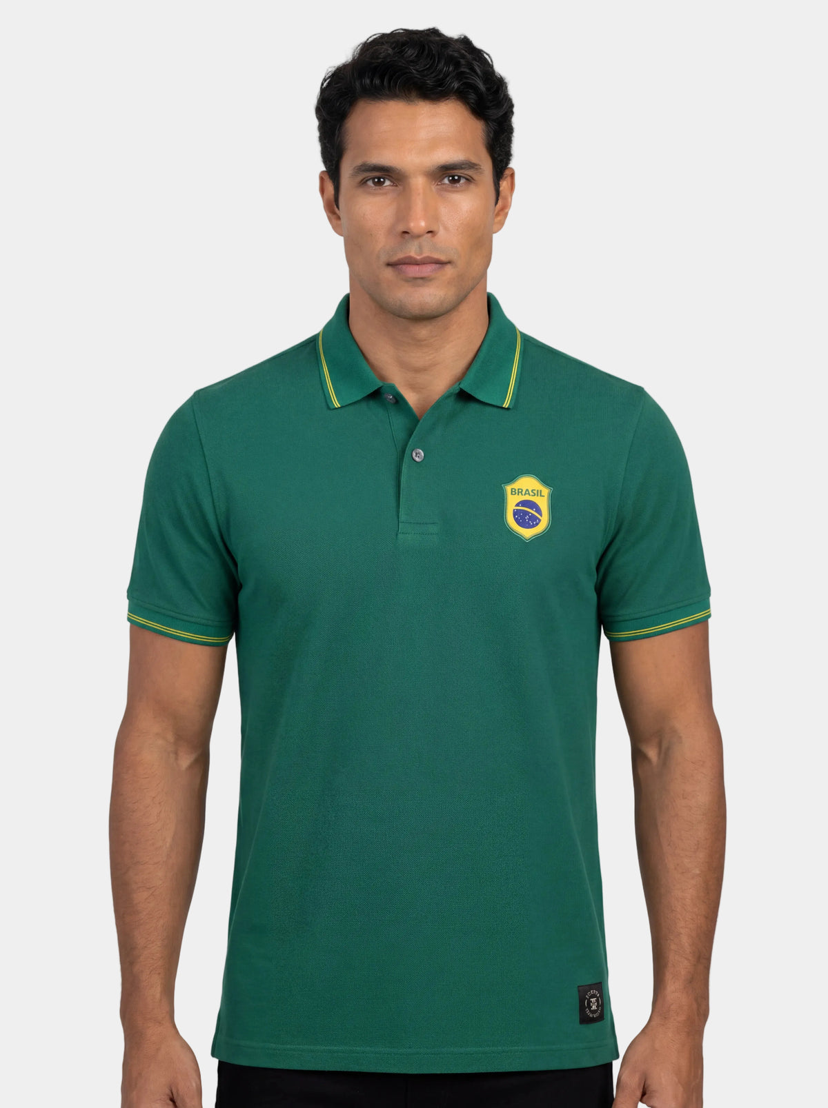 Man wearing a green polo shirt with a logo on a white background