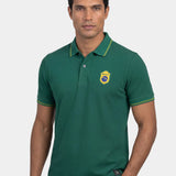Man wearing a green polo shirt with a logo on a white background
