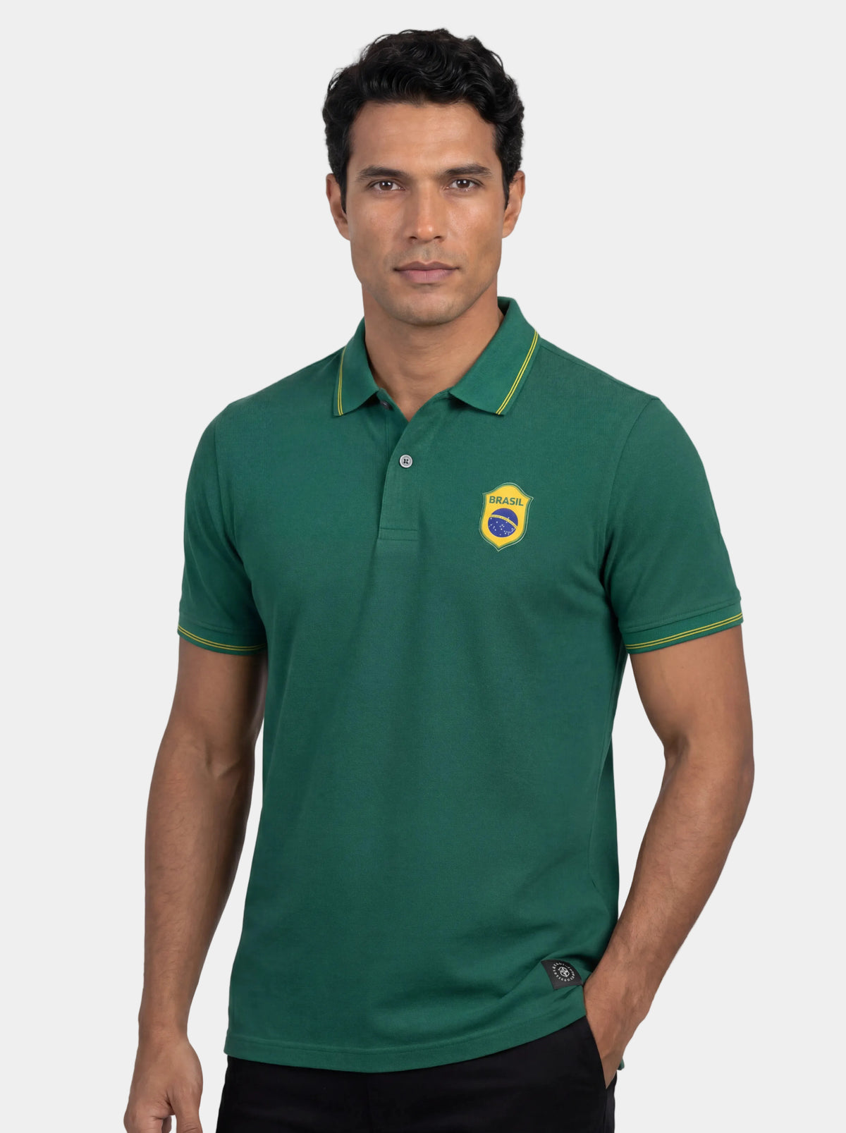 Man wearing a green polo shirt with a logo on a white background