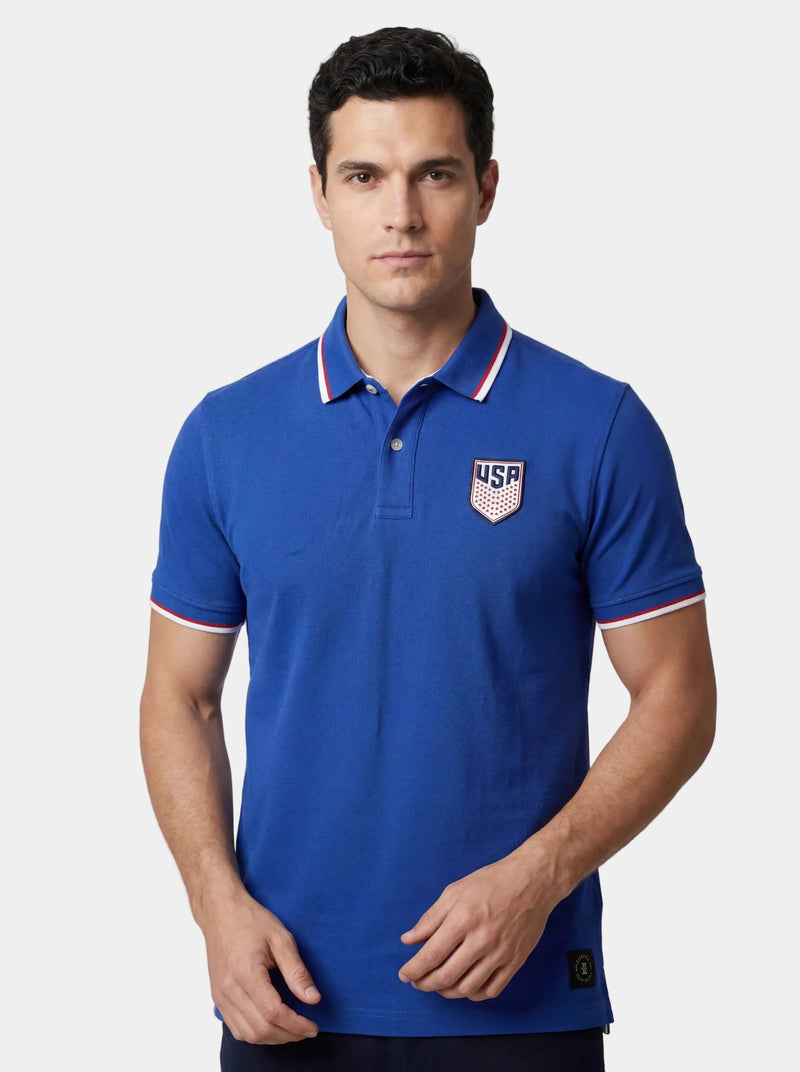Man wearing a blue polo shirt with a USA logo on a light gray background