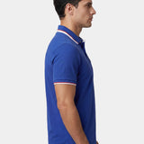 Man wearing a blue polo shirt with white trim on a light gray background.