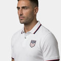Man wearing a white polo shirt with USA logo on a gray background