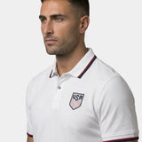 Man wearing a white polo shirt with USA logo on a gray background
